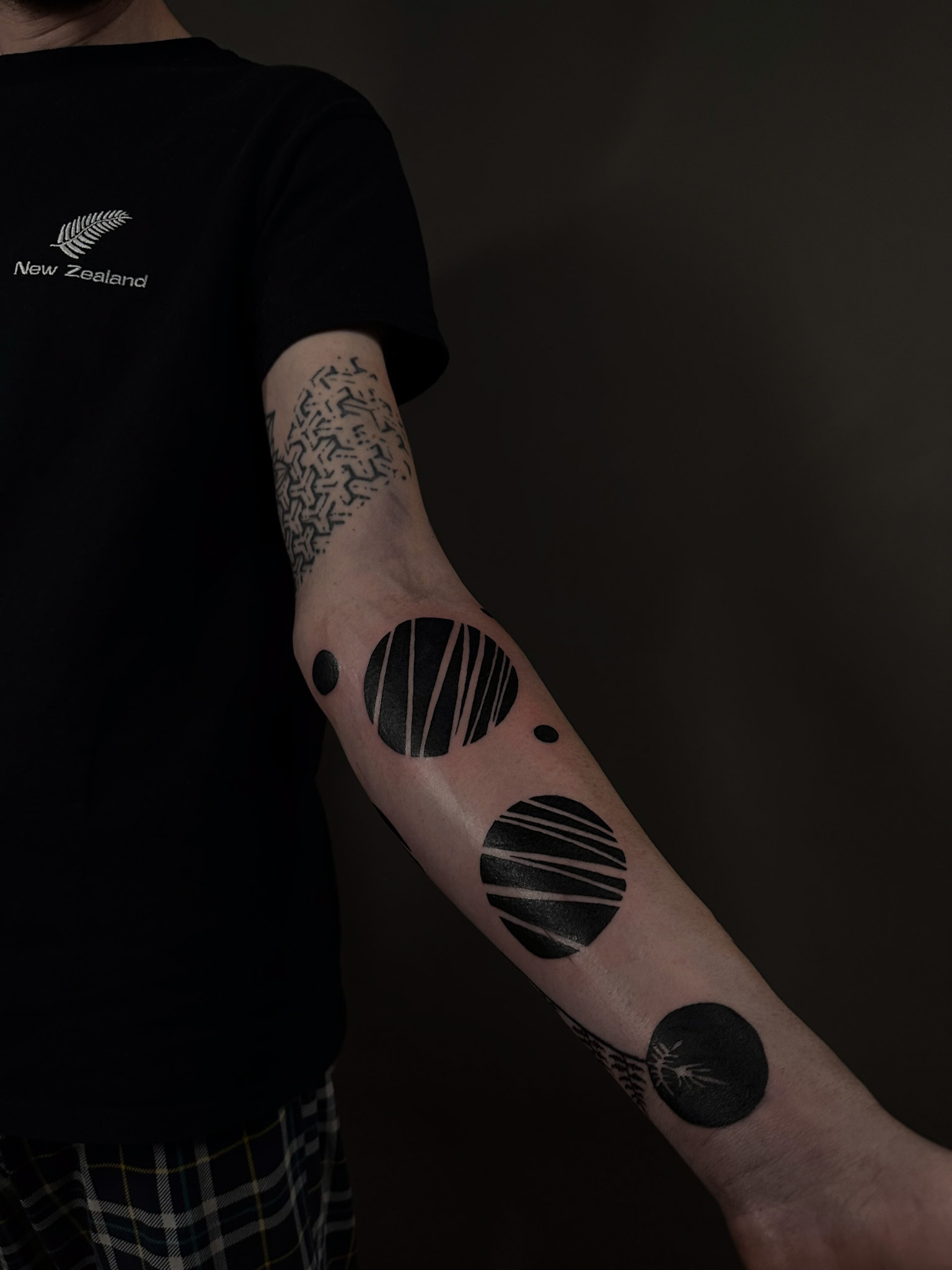 Solid black circles cut with fine lines, running down the forearm