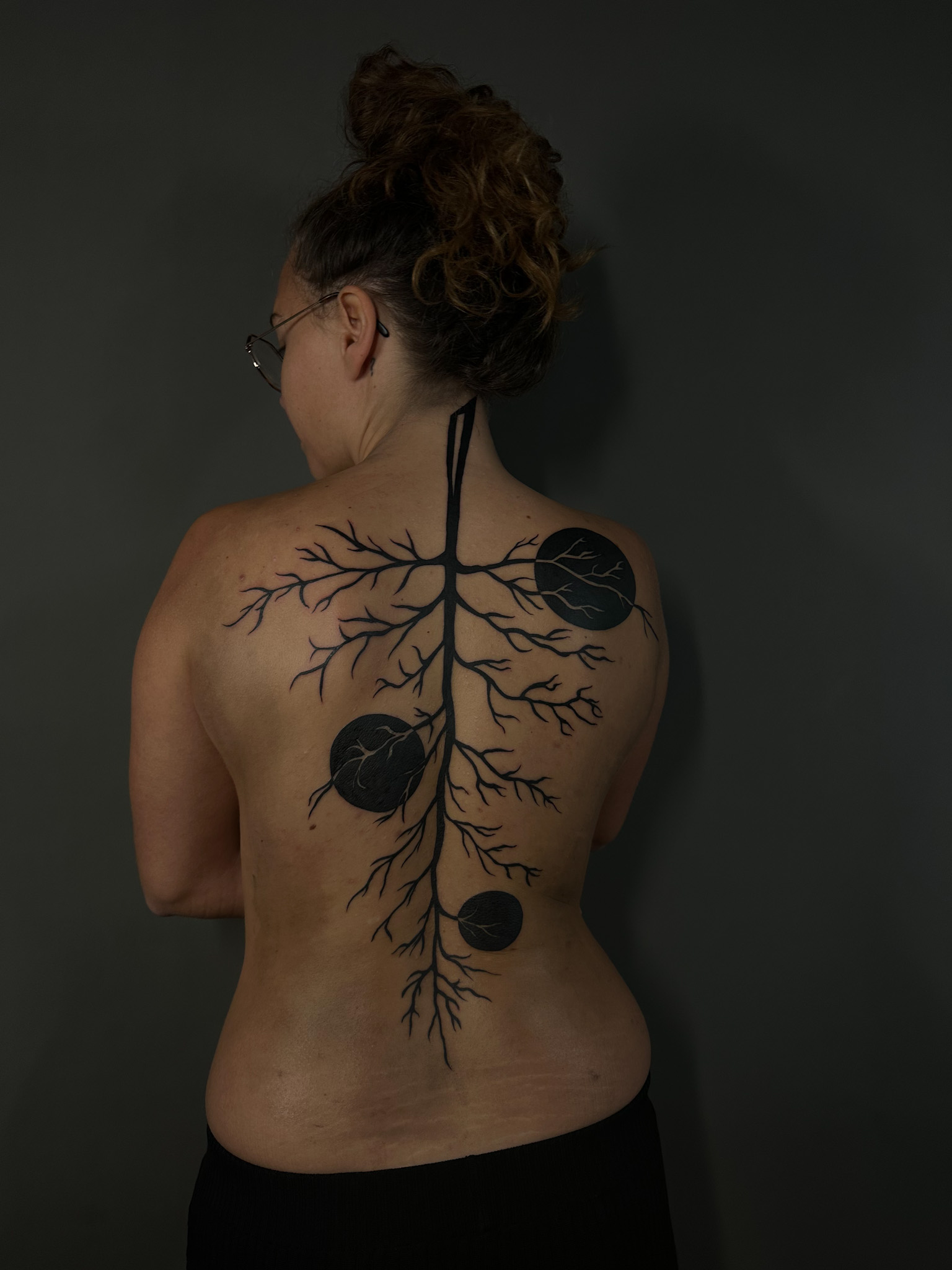 Black branching roots running down the spine, set with solid circles